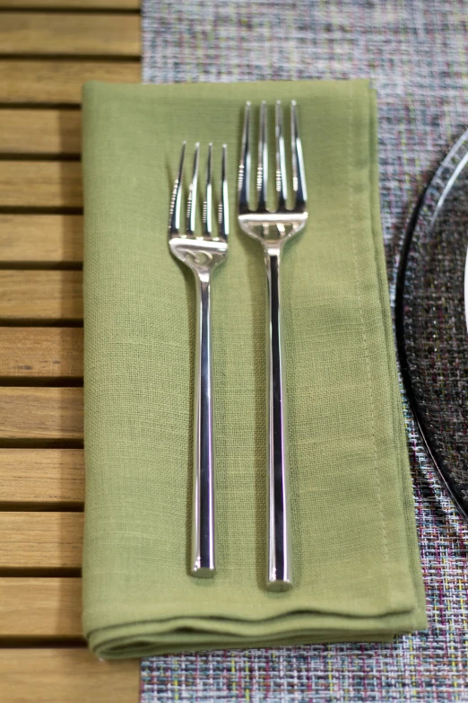 fork, knife and spoon are on a napkin near a plate