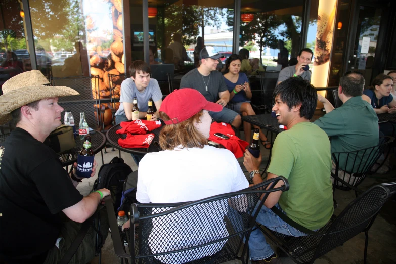 several people sit at tables eating outside while two men talk