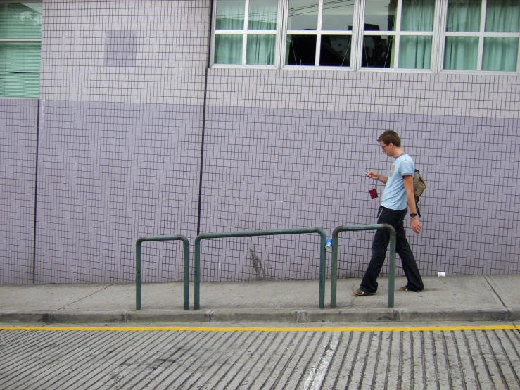 man in jeans and a white shirt using his cellphone on a sidewalk