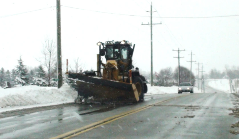 a vehicle driving down a snowy road during the day