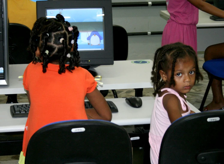 two small children are in front of computers