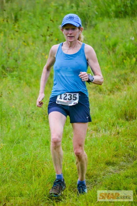 a woman running through some tall green grass