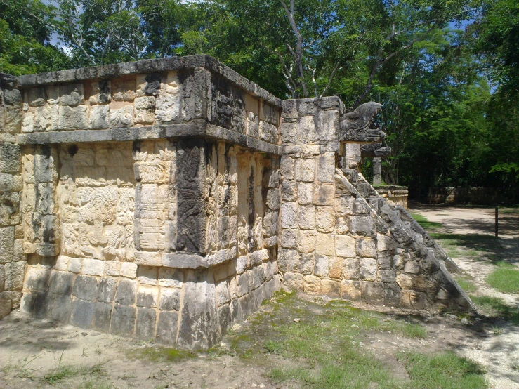 an ancient structure surrounded by trees on a dirt surface