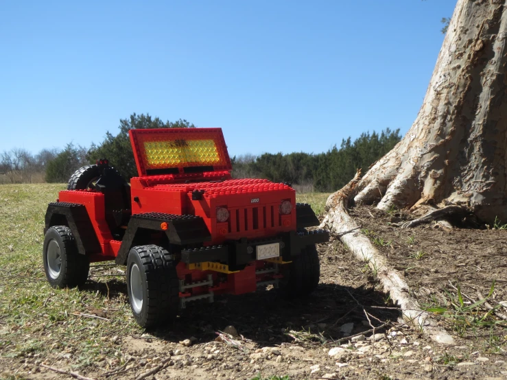 a toy jeep sits beside a tree and a tree