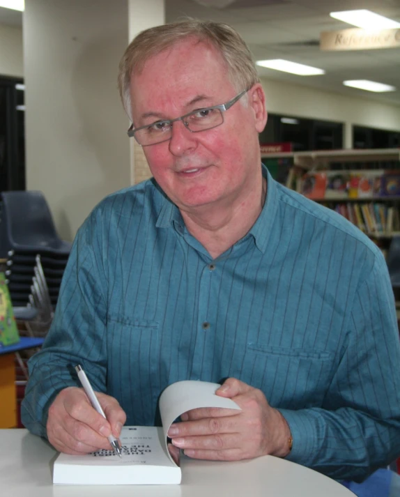 a man writing on paper and holding a coffee mug