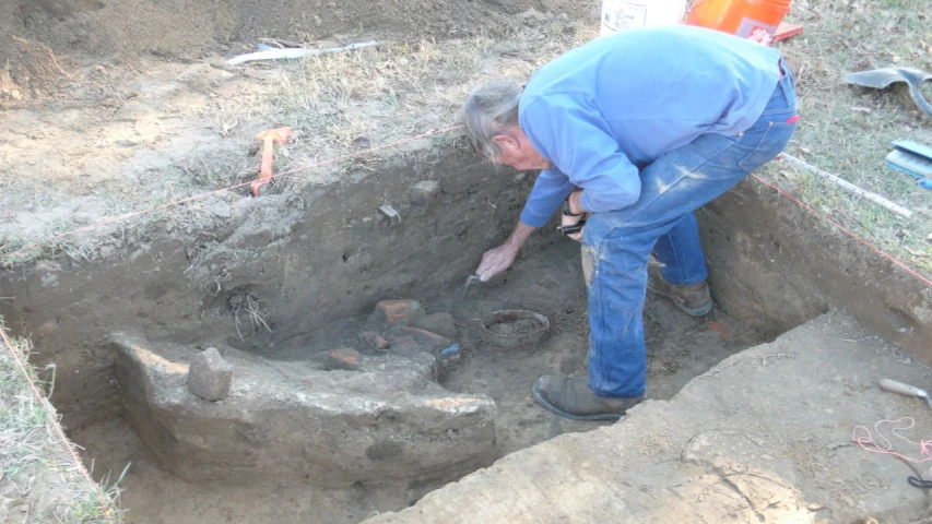 man digging in a large open dirt pit