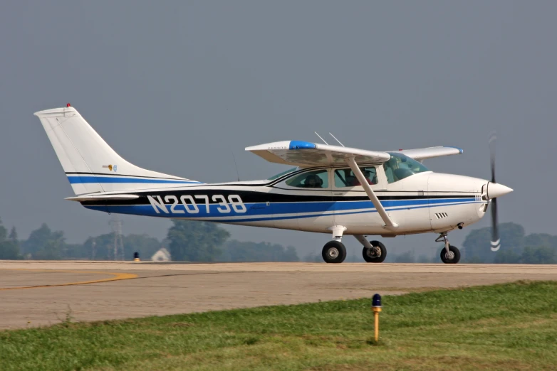 small white airplane with blue stripes landing on the runway
