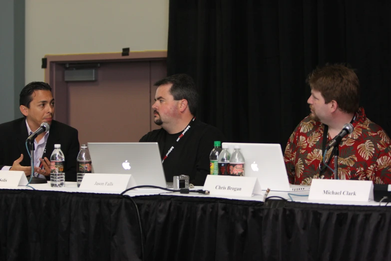 three men on laptops are having discussion at a press conference