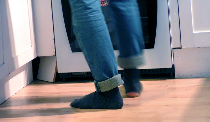 a person wearing gray socks and socks, standing in front of an oven