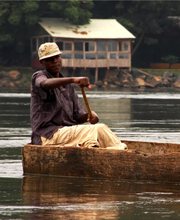 a man sitting in a wooden boat on a lake