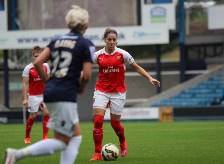 a female soccer player kicks the ball in the midst of other players