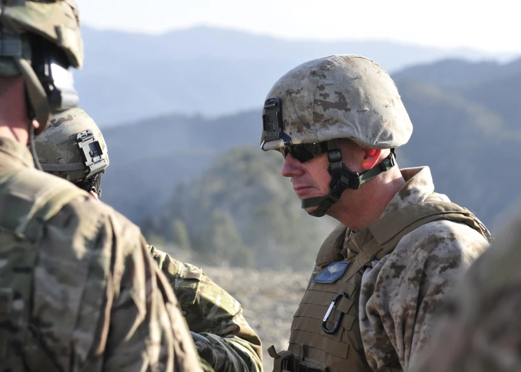 three soldiers are talking together in camouflage clothes