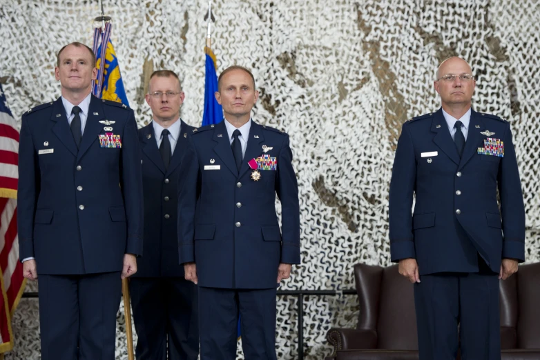 five men standing together in suits and uniforms in a room