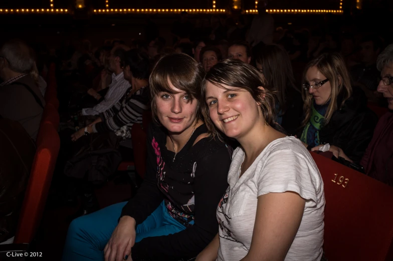 two girls sit together in an audience