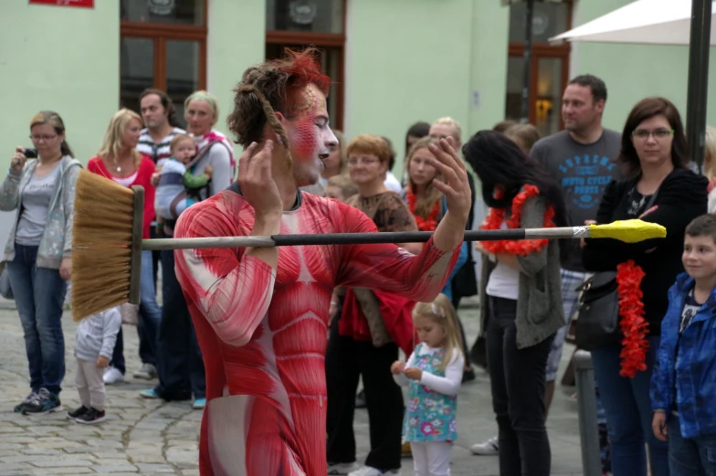 a man with painted face holding a broom and brush