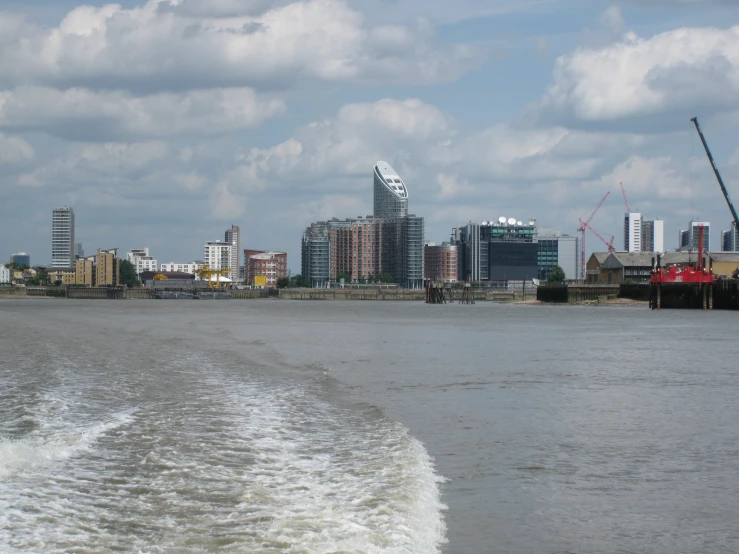 there are many boats in the water with some buildings behind them