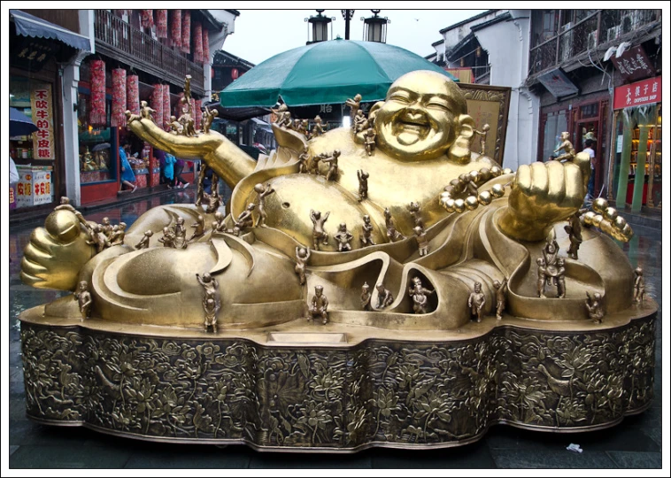 a gold statue of a smiling man with golden hands