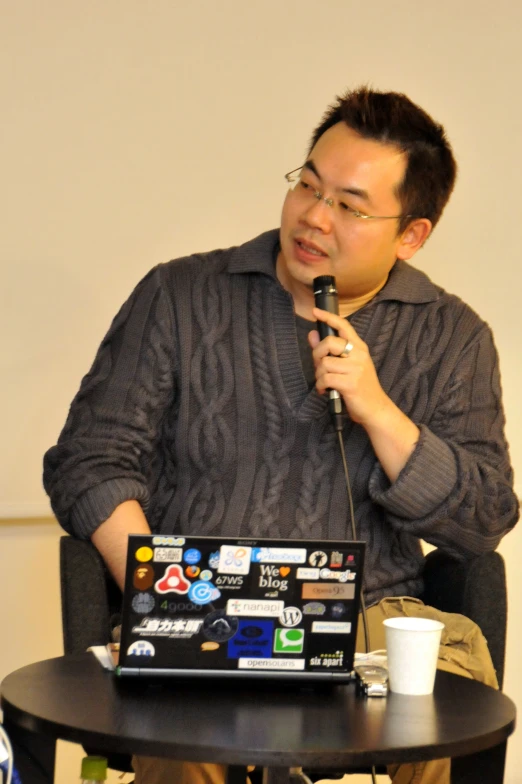 a man holding a microphone in front of a laptop