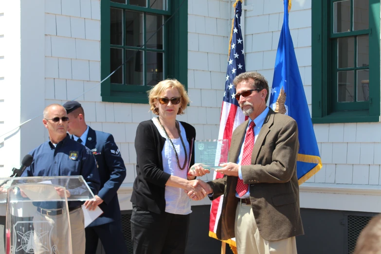 a man and woman shaking hands in front of two flags