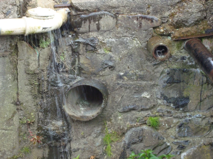 a drain with three pipes on a wall