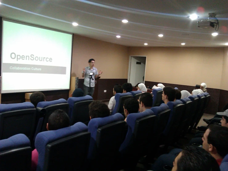 an asian man talking in front of a crowd