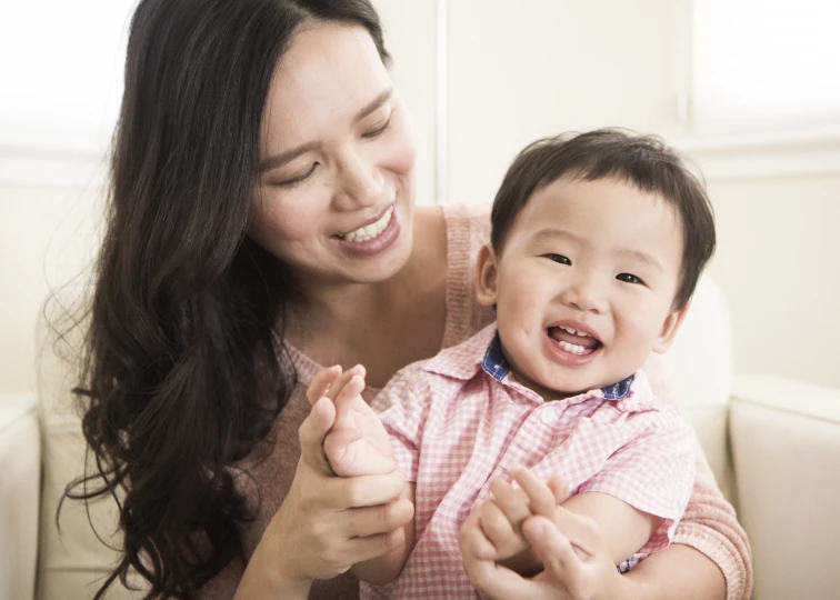 a woman is holding up a baby with long hair