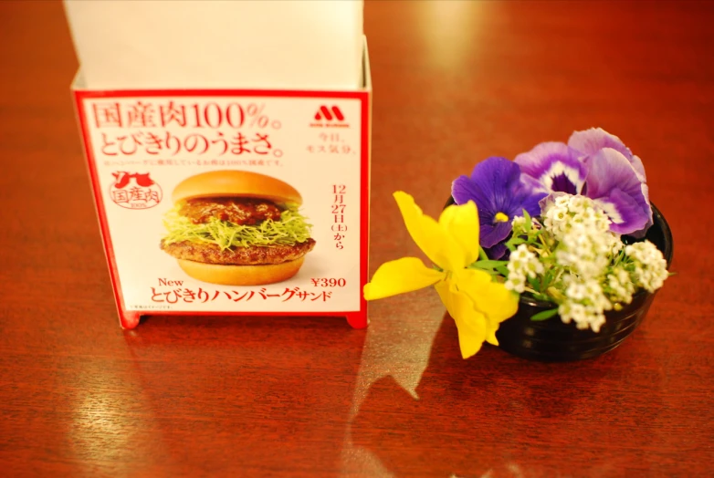 a box with a sandwich next to a flower