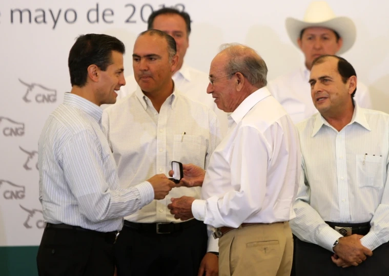 three men standing and shaking hands with another man in the foreground