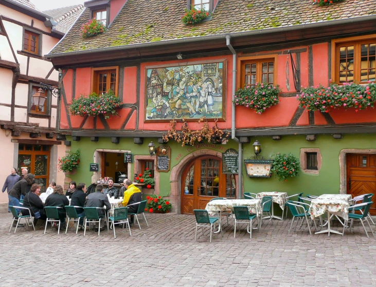 people sitting in patio chairs near small colorful building