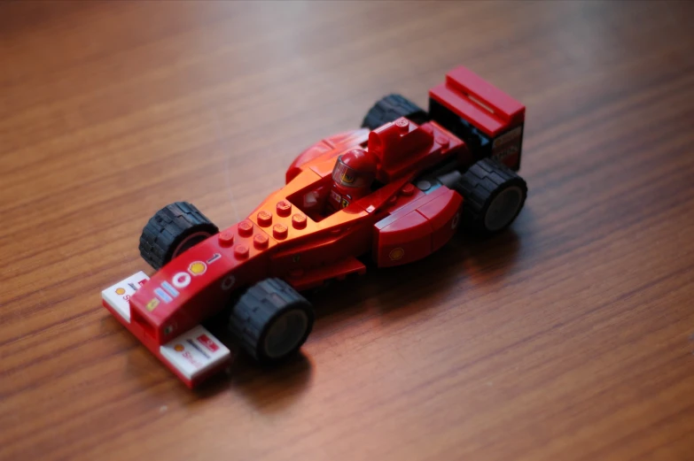 a small toy race car is sitting on a wooden surface