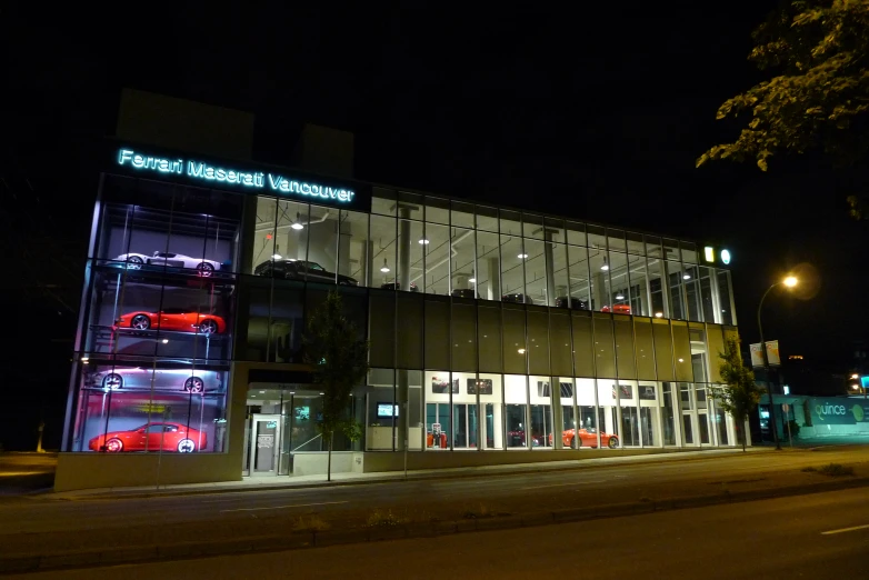 a large glass and steel building with red and black cars