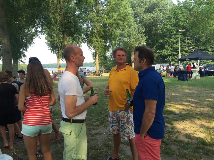 three people talking to each other while standing in a park