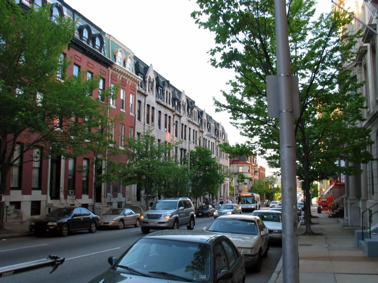 a street with many cars parked in the street and buildings on both sides