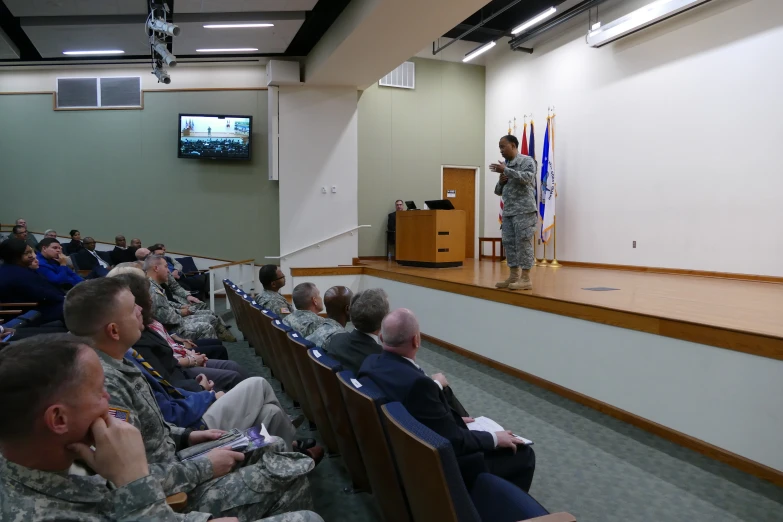 a military conference with several people in rows and the man speaking