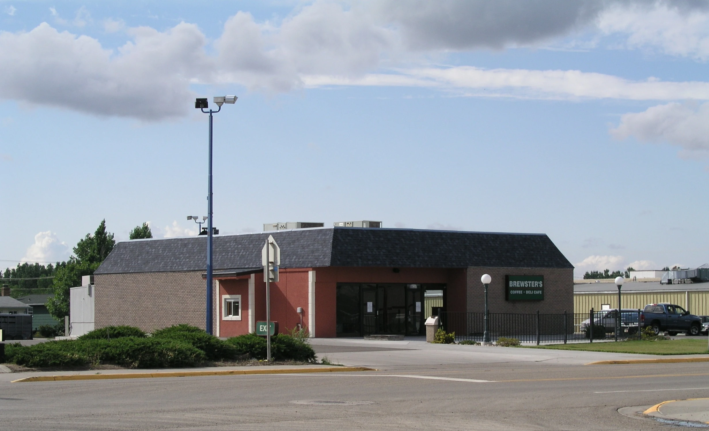 a small building with a clock tower and car parked nearby