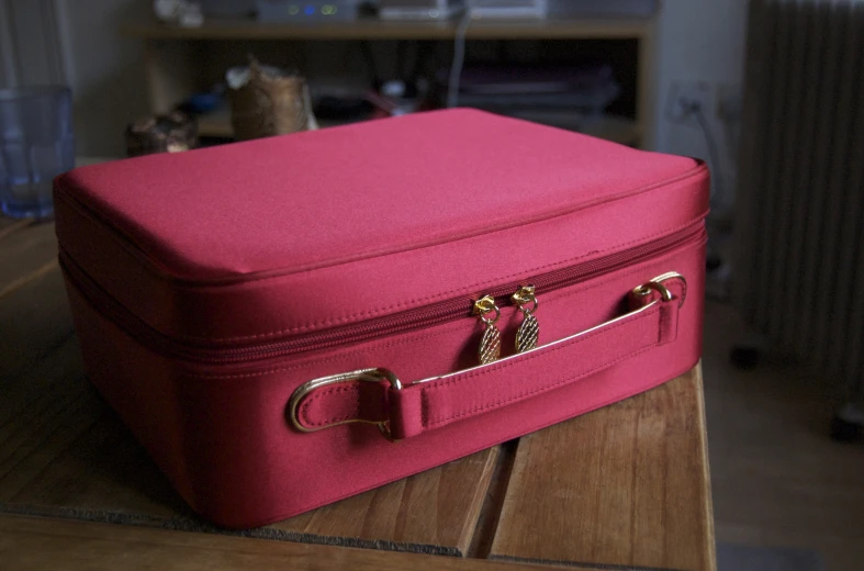 a close up of a pink suitcase on a wooden bench