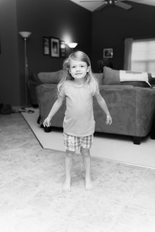 a little girl with her leg up standing in front of the floor