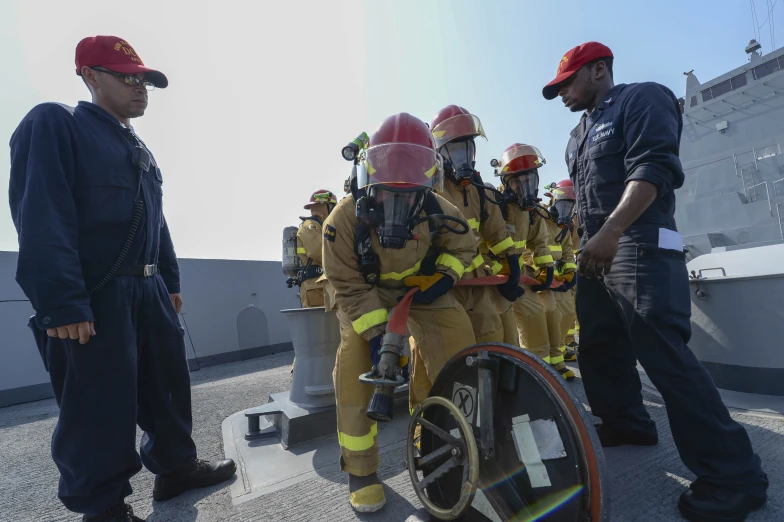 firefighters in uniforms are observing a man on a wheel