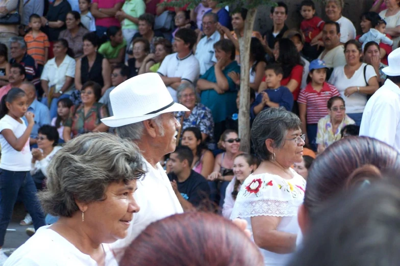 a crowd of people watch a man with a hat