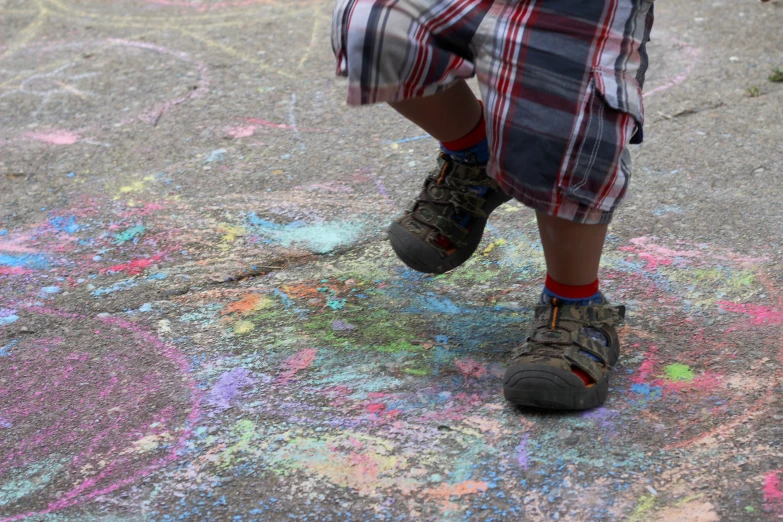 a child's foot with colorful chalk crayons on the sidewalk