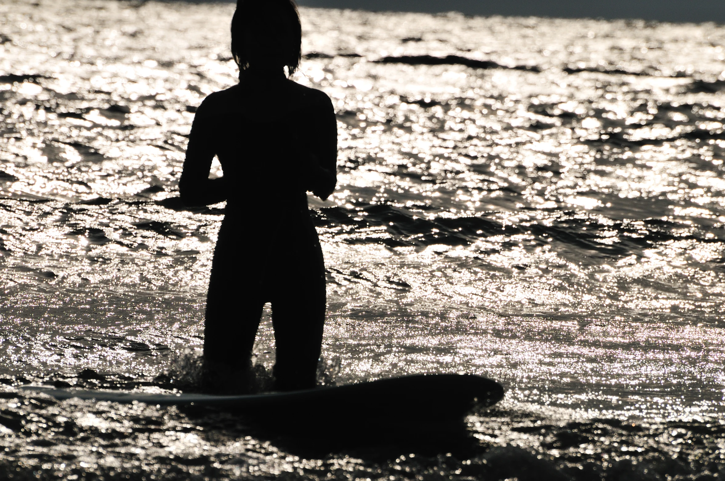 a person in a wetsuit stands in the water with a surf board
