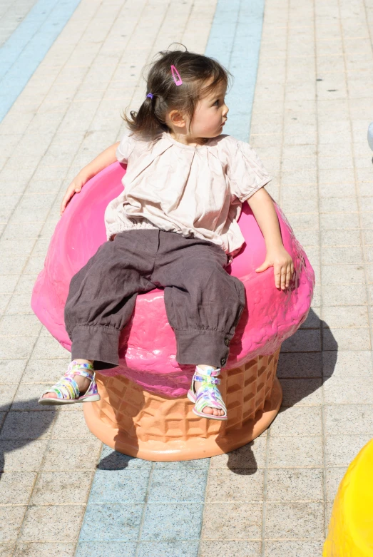 a small child sits in a large pink object