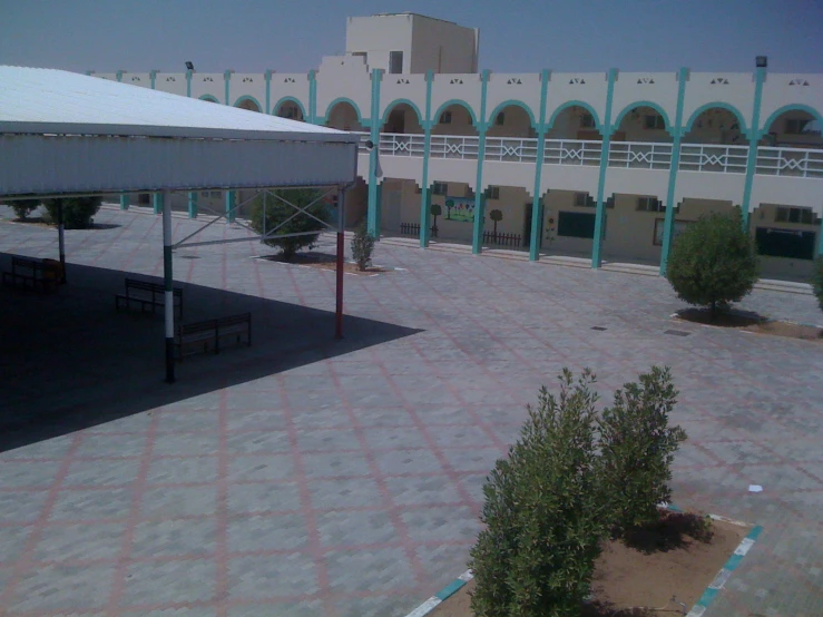 an empty courtyard with a white canopy and several benches