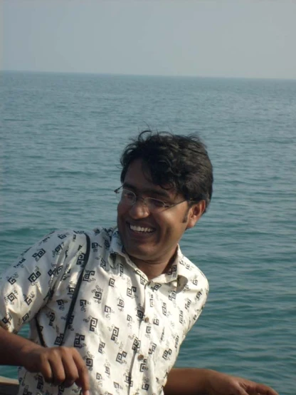 man in patterned shirt sitting in a boat looking around