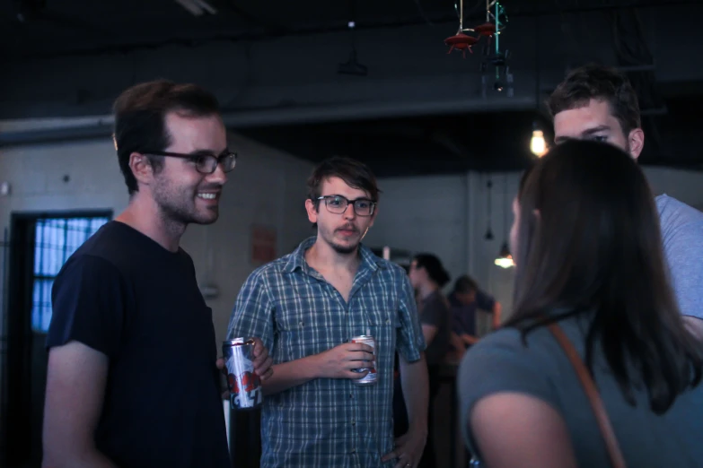 three guys standing in a group talking and drinking beer