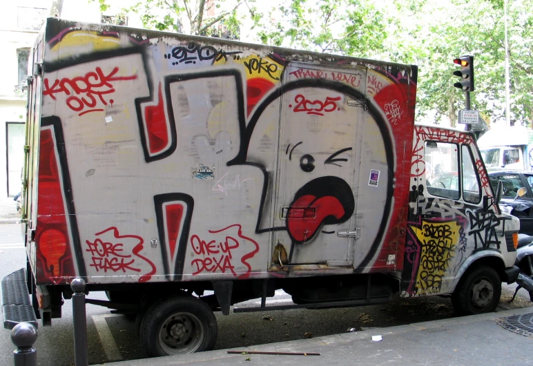a graffitied truck that is on the side of a street
