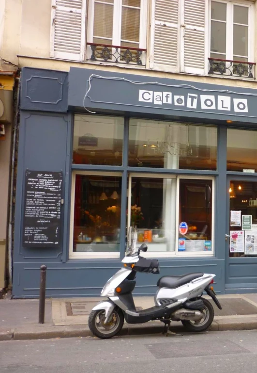 a motor scooter parked outside of a deli that is selling doughnuts