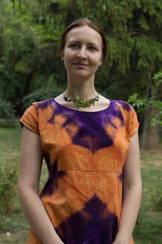 a women who is wearing a colorful dress and necklace