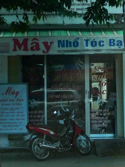 a motorcycle parked in front of a shop called may