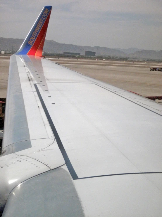 an airplane wing at the airport on a cloudy day